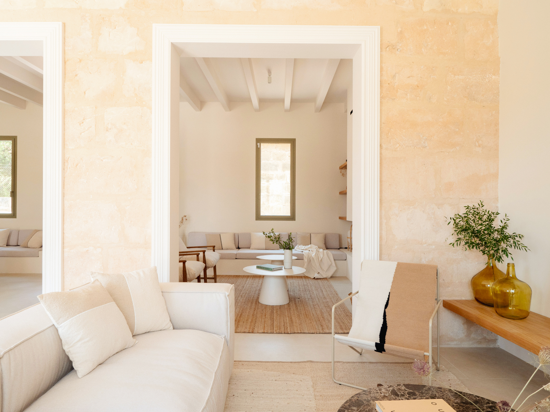 Living room with white sofa, exposed beams and stone walls